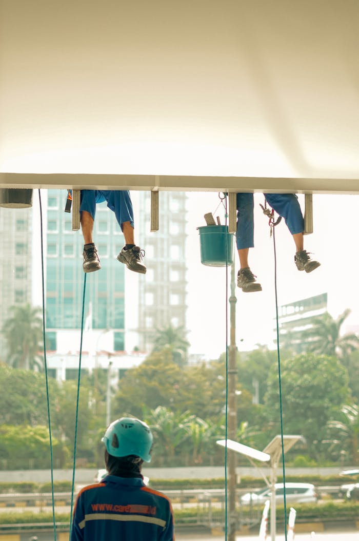 Professional window cleaners maintain a skyscraper's facade with safety gear. Urban scene.